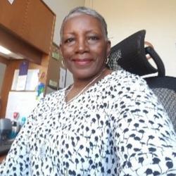 A picture of Renée Dunbar-Scott sitting at a desk smiling. 