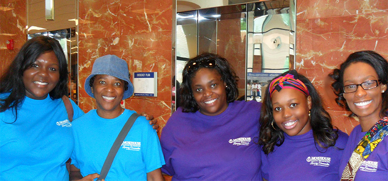 A group of women smile and link arms together