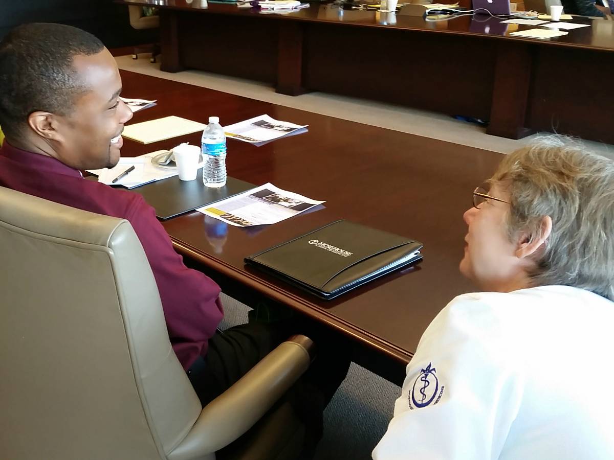 A student sitting a table listens to his mentor