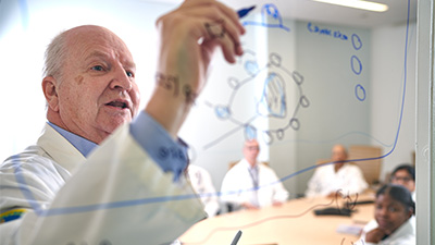 a man writes with a whiteboard marker on a glass panel